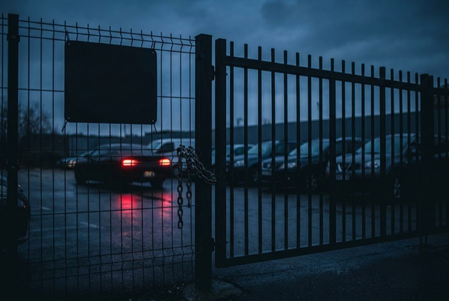 Private parking lot entrance with a tow-away warning sign at dusk
